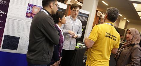 Discussion between 5 people at a booth at CIUK conference