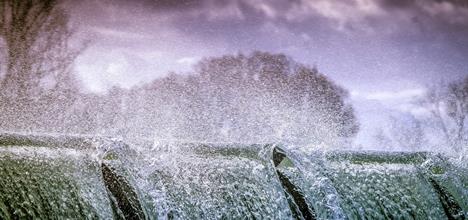 Close up of the top of a waterfall, with aggressive waterspray obscuring most of the background.