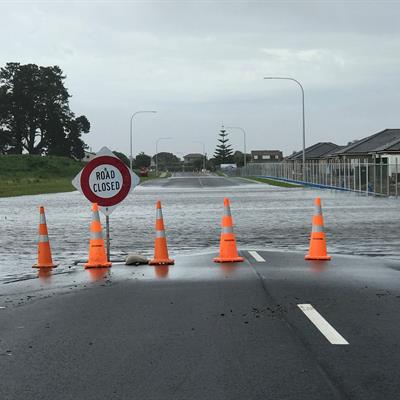 Flooded road with orange cones and road closed sign